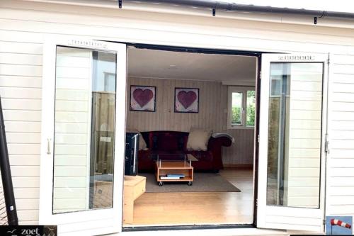 a sliding glass door of a living room with a couch at Holiday-Chalet Westenwind 4p. Amsterdam & Beach in Opmeer