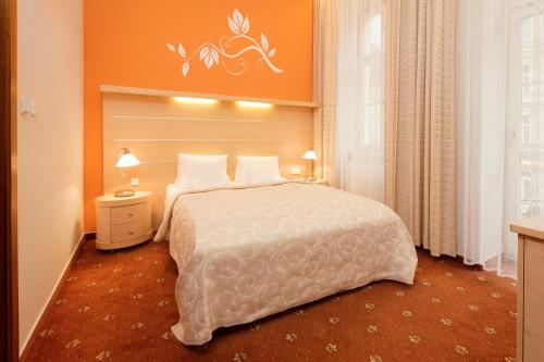 a bedroom with a large bed with an orange wall at Venus in Karlovy Vary