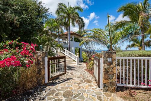 a gate leading to a house with palm trees and flowers at TAMAR VILLA in Virgin Gorda