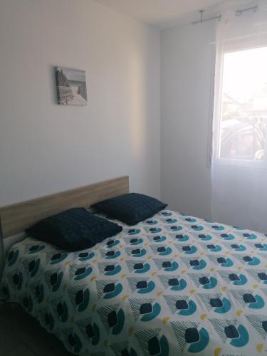 a bedroom with a bed with a floral comforter and a window at La gravière in Saint-Geours-de-Maremne