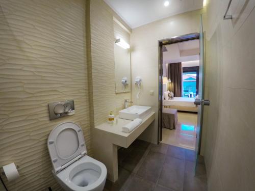 a bathroom with a toilet and a sink and a mirror at Arion suites in Sarti