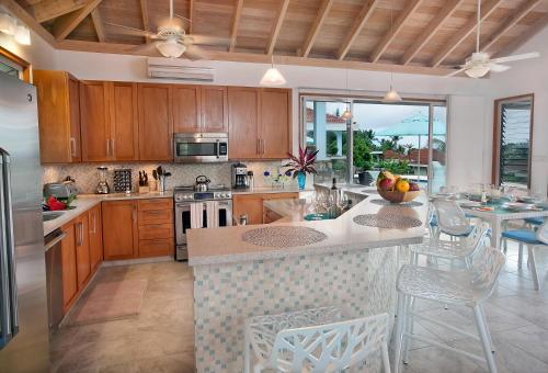 a kitchen with wooden cabinets and a kitchen island with chairs at BLUE LAGOON in Virgin Gorda