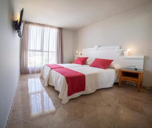 Puerta Salinas Isla Cristina في إيسلا كريستينا: غرفة نوم مع سرير أبيض كبير مع وسائد حمراء
