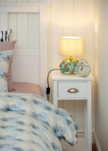a bed with a nightstand with a lamp and a clock at Sea View Studio Apartments by the Beach in Ihasalu