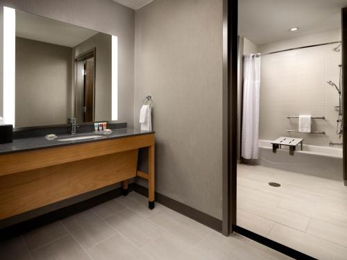 a bathroom with a sink and a mirror and a tub at Hyatt Place Amarillo-West in Amarillo