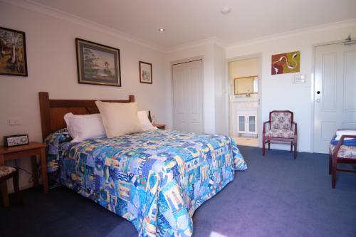 a hotel room with a bed, chair, and table at Anchors Aweigh - Adult Only in Narooma