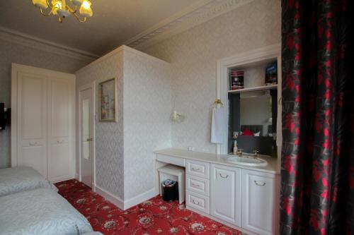 łazienka z umywalką, lustrem i łóżkiem w obiekcie Dunallan Guest House w mieście Perth