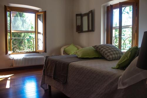 a bedroom with a bed with green pillows and two windows at RESIDENZA LE CICOGNE in Pistoia