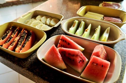 a bunch of trays filled with watermelon and other fruits at Pousada Casa Do Angelo in Jericoacoara