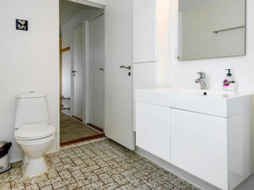a white bathroom with a toilet and a sink at Holiday Home Kraghøjvej in Kolind