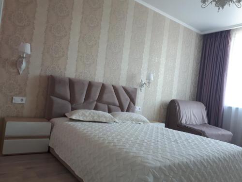 Un dormitorio con una cama blanca y una silla. en Apartments Lutsdorf, en Odessa