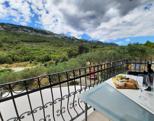 a table with a plate of food and wine glasses on a balcony at Apartments Pitve in Jelsa