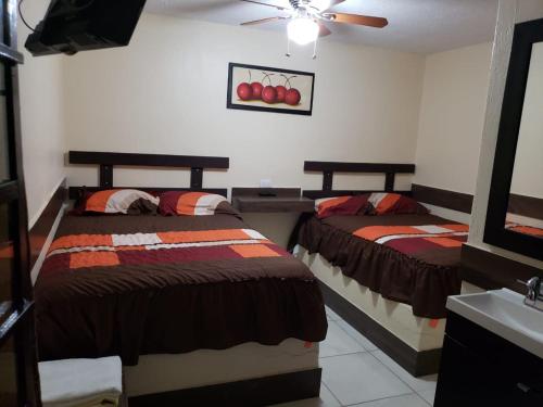 a bedroom with two beds and a ceiling fan at Hotel Santa Ana in Guadalajara