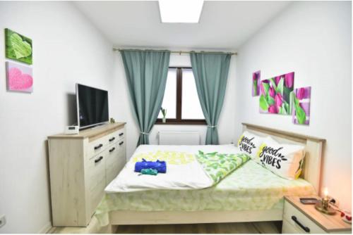 a small bedroom with a bed and a television at Good Vibes Apartament in Braşov