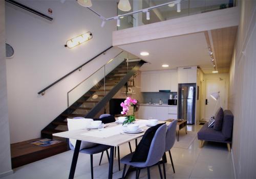 une salle à manger avec une table, des chaises et un escalier dans l'établissement MLH Designer Duplex Suite @ EkoCheras, à Cheras