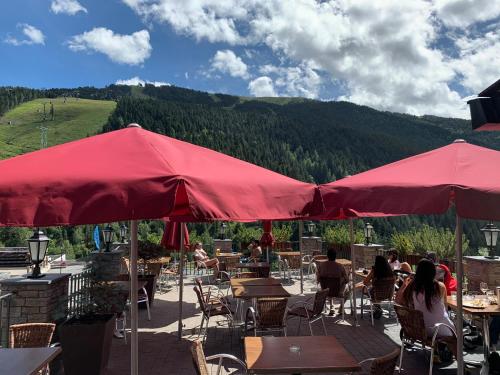 a patio with tables and chairs and red umbrellas at Hôtel Bruxelles in Soldeu