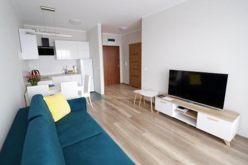 Il comprend un salon doté d'un canapé bleu et d'une télévision à écran plat. dans l'établissement Apartament Cukrownia, à Szczecin