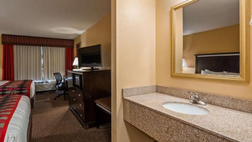a hotel room with a sink and a bed and a mirror at Best Western Plus Bessemer in Bessemer
