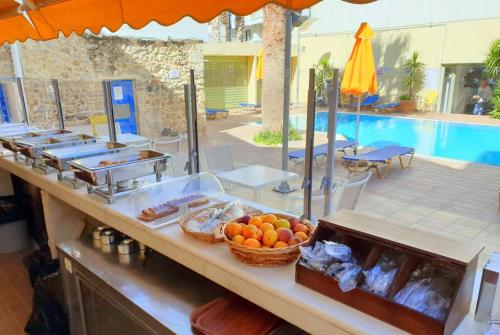 a buffet with fruit on a counter next to a pool at Kassavetis Center - Hotel Studios & Apartments in Hersonissos
