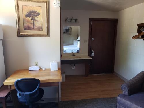 een kamer met een bureau, een wastafel en een spiegel bij Autumn's Inn in Roundup