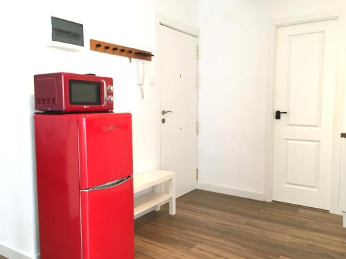 a red refrigerator with a tv on top of it at Mar y Arena - 5 minutos a la playa y al centro in Santa Pola