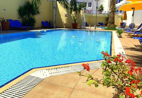 a swimming pool in a hotel with blue chairs and flowers at Kassavetis Center - Hotel Studios & Apartments in Hersonissos