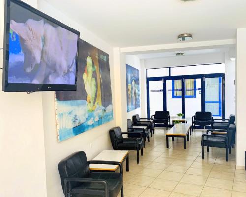 a waiting room with chairs and tables and a large screen at Kassavetis Center - Hotel Studios & Apartments in Hersonissos