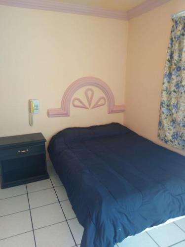 a bedroom with a blue bed and a night stand at Hotel Plaza Peñasco in Puerto Peñasco