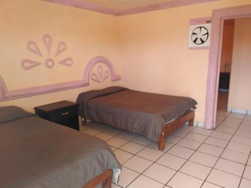 a room with two beds and a clock on the wall at Hotel Plaza Peñasco in Puerto Peñasco
