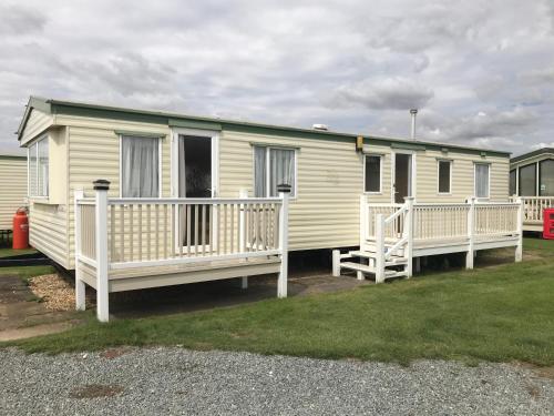 a yellow mobile home with a porch and a deck at Golden Sands Ingoldmells (Atlantis) in Skegness