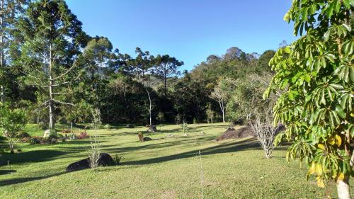 a park with grass and trees on a sunny day at Chalés Das Estrelas in Visconde De Maua