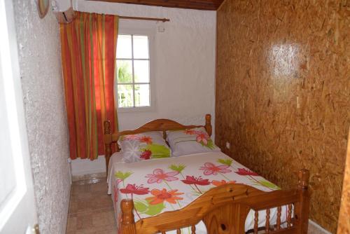 a bedroom with a bed with a floral bedspread and a window at LE VILLAGE DE CANADA in Faup