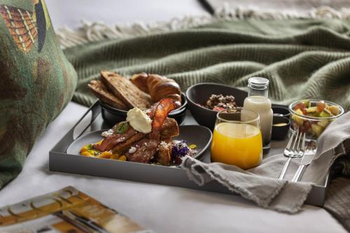 a tray of food with breakfast foods and orange juice at Hotel Fitzroy curated by Fable in Auckland