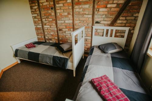 twee bedden in een kamer met een bakstenen muur bij Salas Holiday Home in Jūrkalne