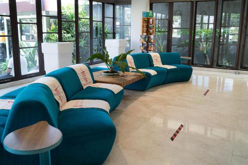 a row of blue couches in a room with windows at Grand Livio Kuta Hotel in Legian