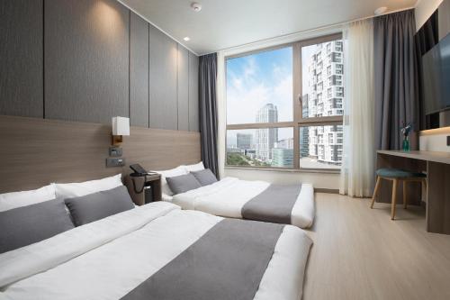 a hotel room with two beds and a large window at Utop Boutique Hotel&Residence in Gwangju