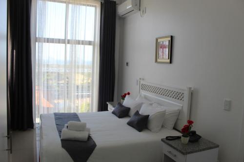 sypialnia z białym łóżkiem i dużym oknem w obiekcie Royal Ushaka Hotel Morningside w mieście Durban