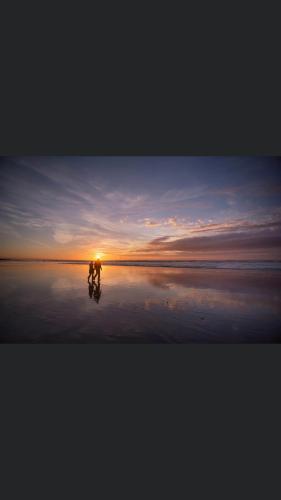 a person riding a bike on the beach at sunset at Escale beauté le Crotoy in Le Crotoy