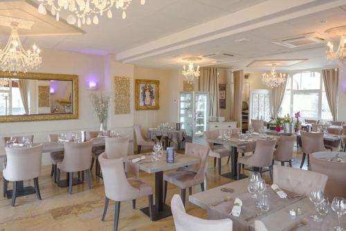 une salle à manger avec des tables, des chaises et des lustres dans l'établissement Hôtel Le Vouglans - Restaurant La Valouse, à Orgelet