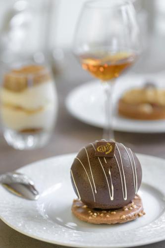 a chocolate dessert on a white plate with a spoon at Hôtel Le Vouglans - Restaurant La Valouse in Orgelet