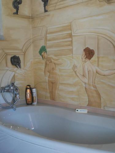 baño con bañera con una pintura en la pared en Antico Casale dei Sogni agriturismo, en Lugo