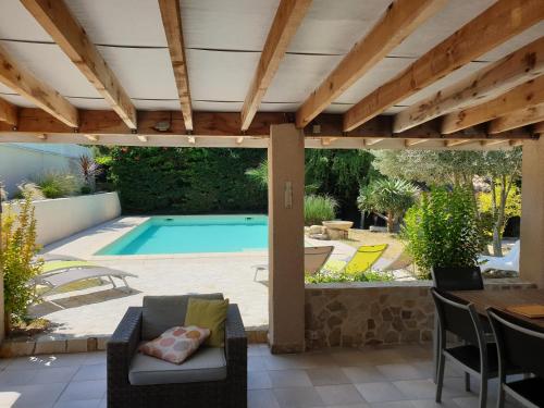 une terrasse avec une piscine et une pergola en bois dans l'établissement Les Hauts de Chaudeyrac, à Bagnols-sur-Cèze