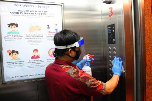 a woman is looking at a sign on an elevator at Best Western Senayan in Jakarta