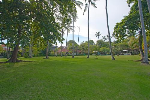 a park with palm trees and lush green grass at Natah Bale Villas in Sanur