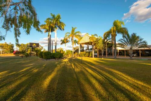 a park with palm trees and a building at Albert Park Motor Inn in Longreach