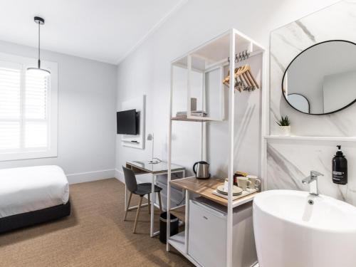 a bedroom with a bed and a sink and a mirror at The Baxley Bondi in Sydney