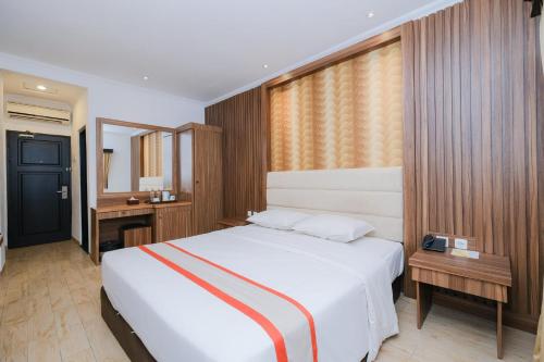 a bedroom with a large white bed and a window at The Grand Palace Hotel Yogyakarta in Yogyakarta