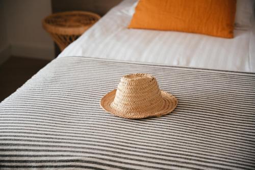 a straw hat sitting on top of a bed at Hôtel Casa Marina in Saintes-Maries-de-la-Mer