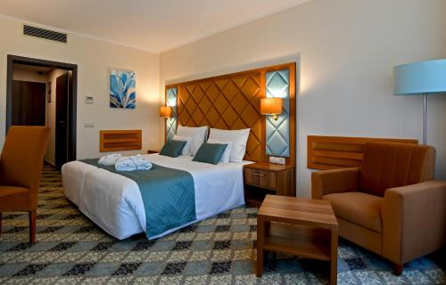 a hotel room with a large bed and a chair at Wellness Hotel Gyula in Gyula