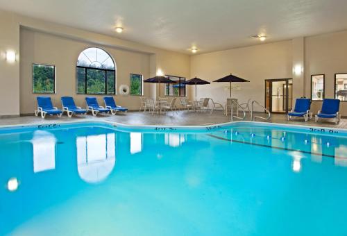 a large swimming pool with blue chairs and umbrellas at Holiday Inn Express Hotel Pittsburgh-North/Harmarville by IHG in Harmarville